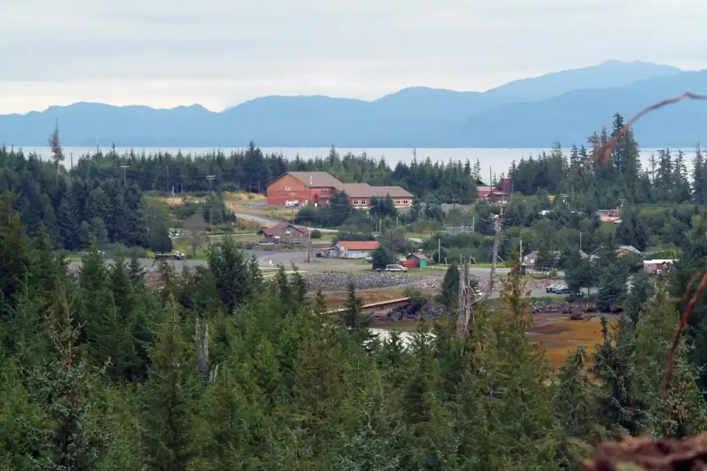 A town sits on the shore of a the ocean, with large mountain ranges behind.