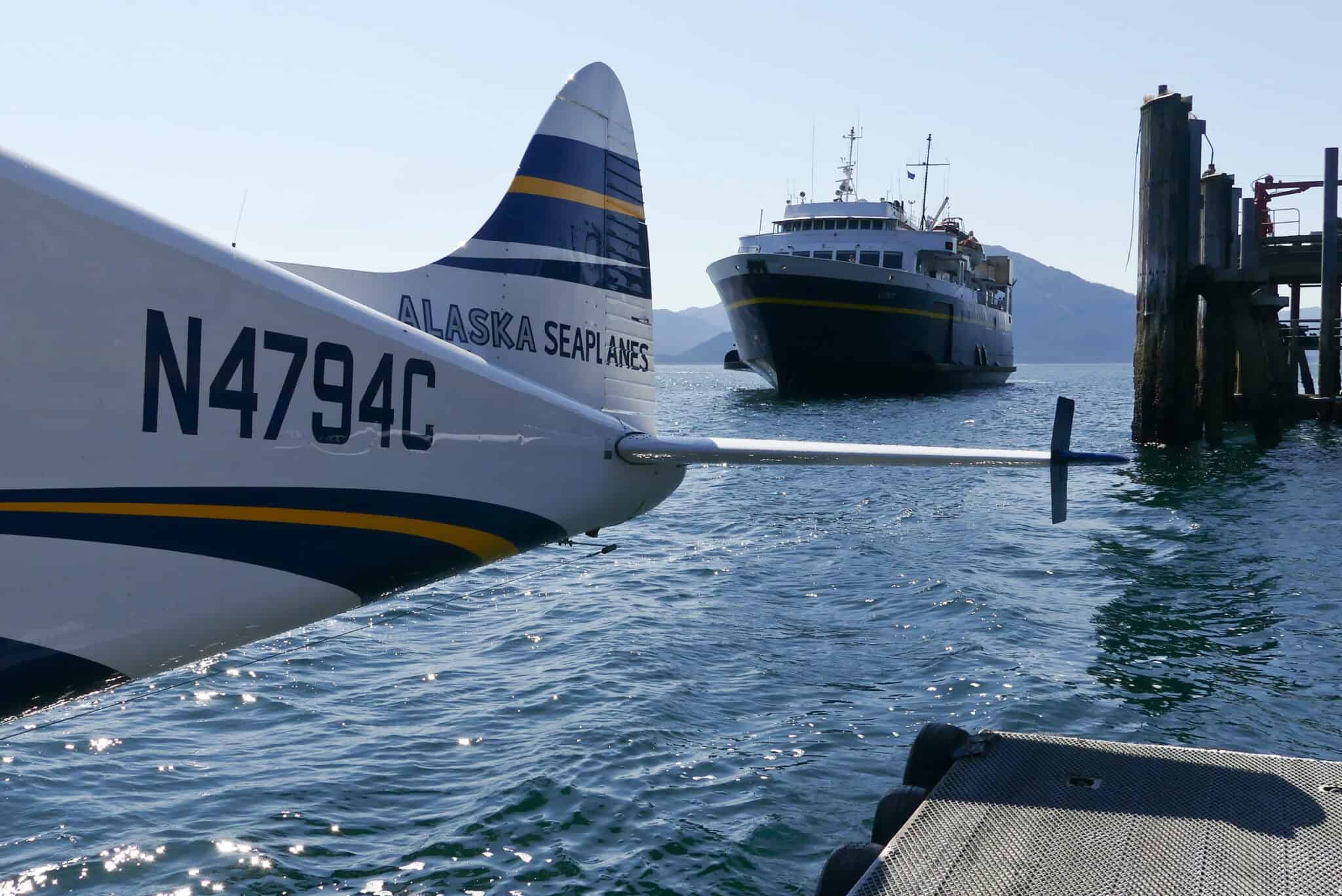 A small seaplane is parked next to a large boat.