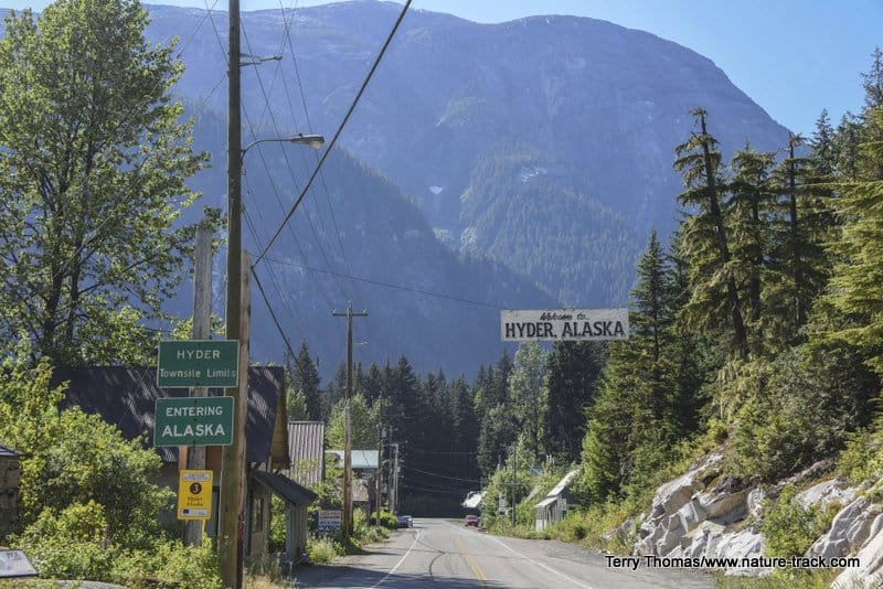A street with a sign that says "lake city" and mountains in the background.
