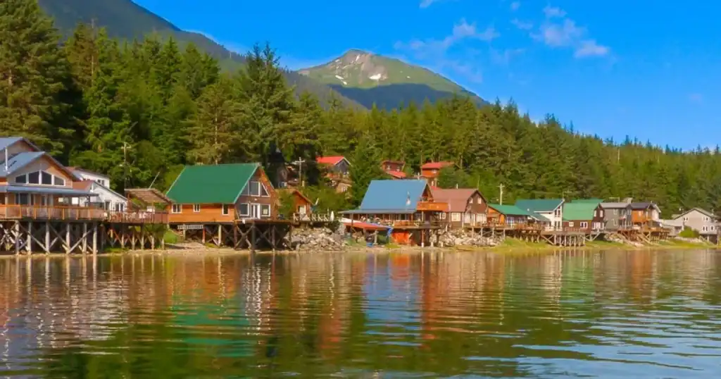 A row of wooden houses on the shore of a body of water.