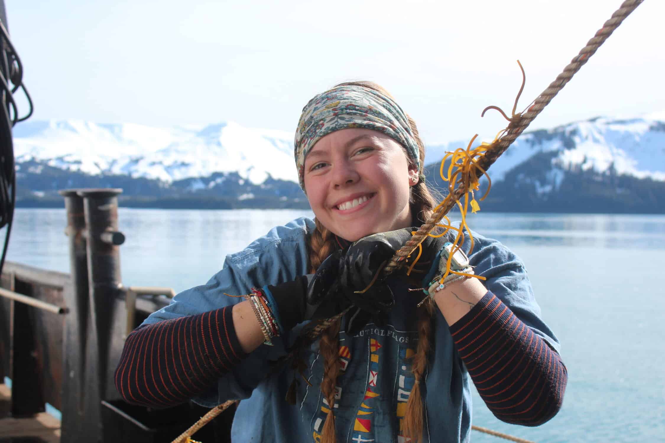 A woman is smiling while holding onto a rope.
