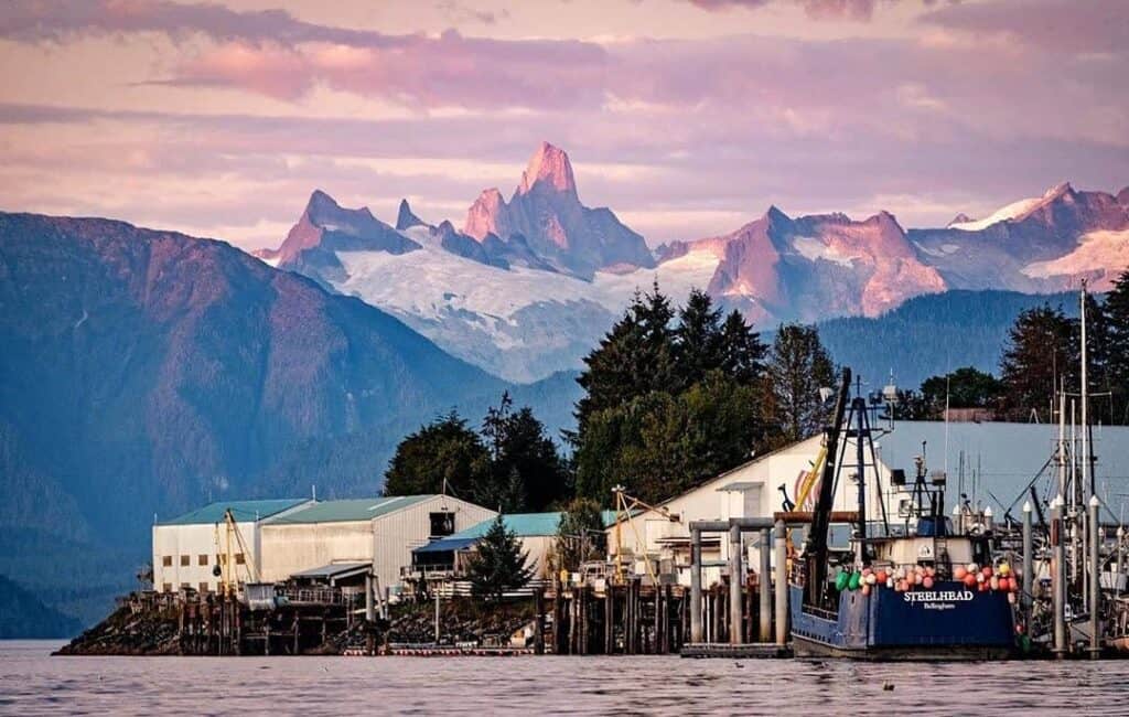 A boat is docked in front of a mountain range.